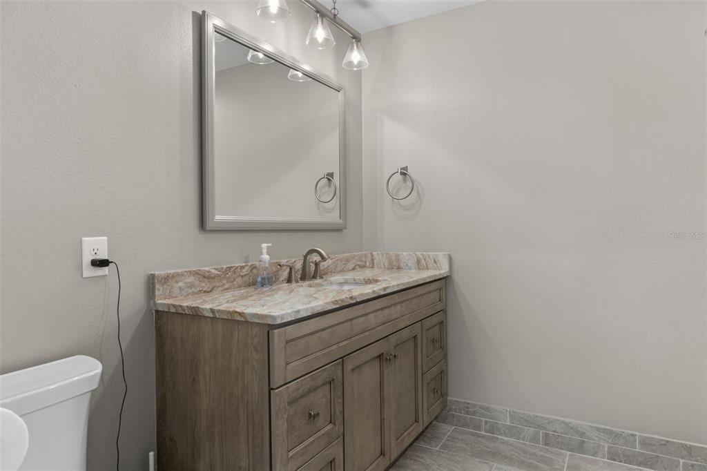 7606 Landmark Drive Spring Hill, FL 34606 - Photo 20 of 41 a bathroom with a granite countertop sink a toilet and a mirror