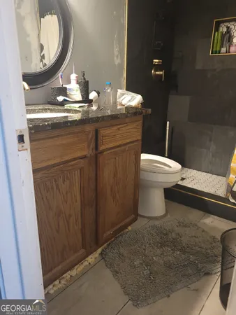 a bathroom with a granite countertop toilet sink and mirror