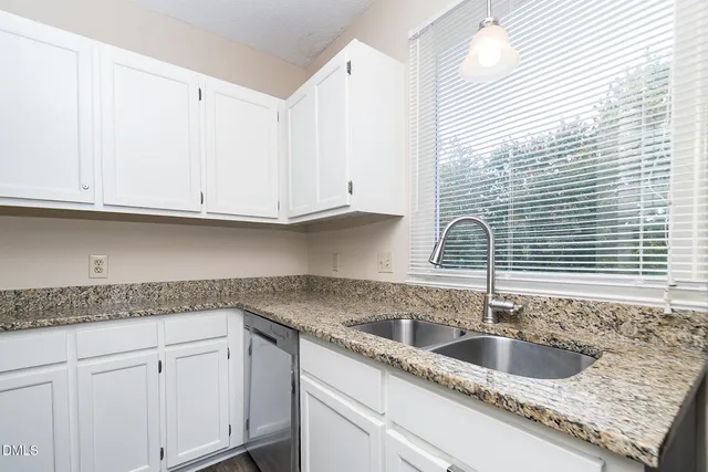 a kitchen with granite countertop white cabinets and a sink