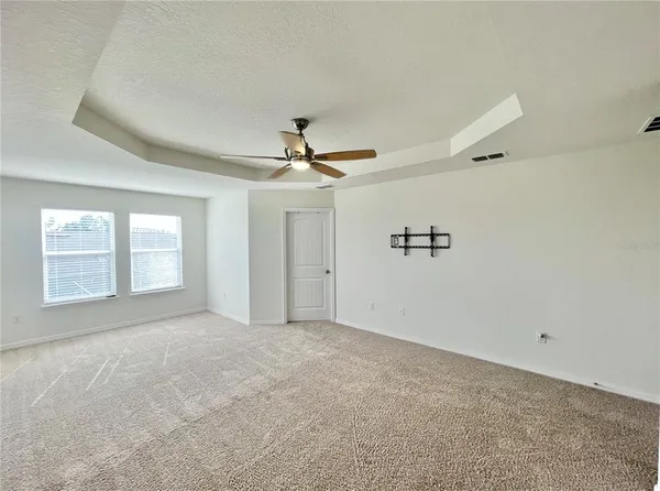 an empty room with windows and fan