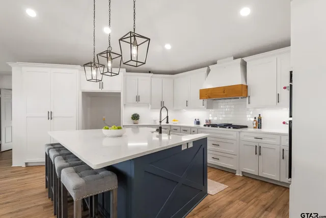 a kitchen with stainless steel appliances granite countertop a sink a stove a dining table and chairs