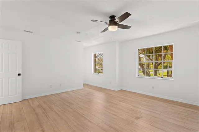 a view of empty room with wooden floor and fan