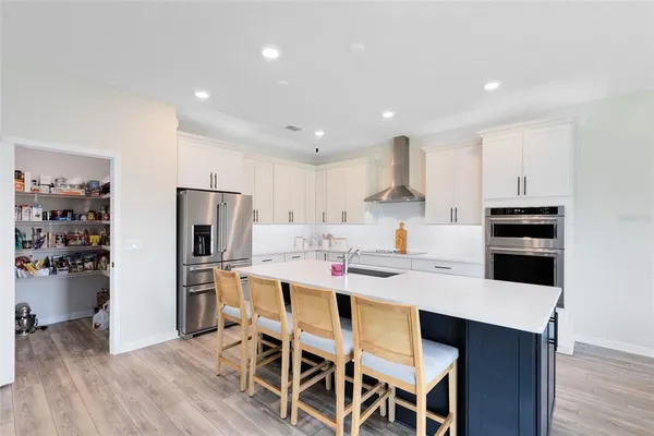 a kitchen with a dining table cabinets appliances and wooden floor