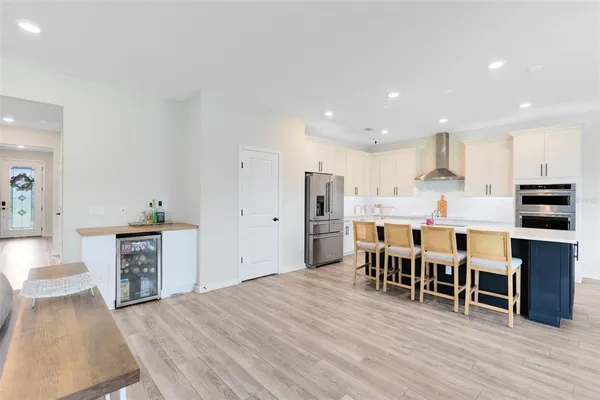 a kitchen with stainless steel appliances a stove top oven a sink dishwasher and a dining table with wooden floor