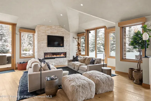 a living room with couches a flat tv screen and a large window with garden view