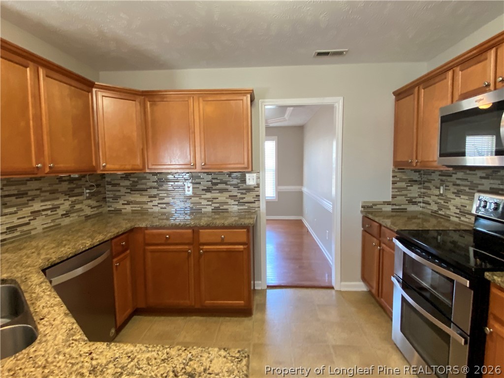 58 Polk Street Spring Lake, NC 28390 - Photo 6 of 26 a kitchen with stainless steel appliances granite countertop a stove a sink and a microwave