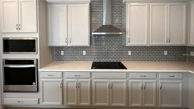 a kitchen with white cabinets a sink a stove and a window