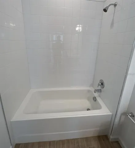 an empty room with wooden floor and shower