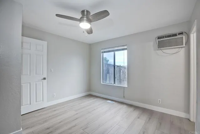 an empty room with wooden floor fan and windows