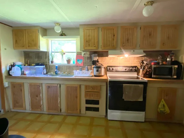 a kitchen with stainless steel appliances granite countertop a stove a sink and a microwave