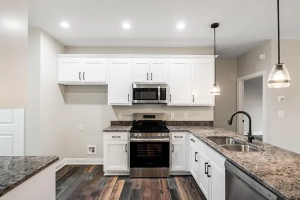 a kitchen with stainless steel appliances granite countertop a stove a sink and a microwave