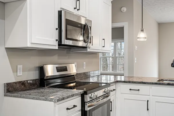 a kitchen with granite countertop a stove microwave and cabinets