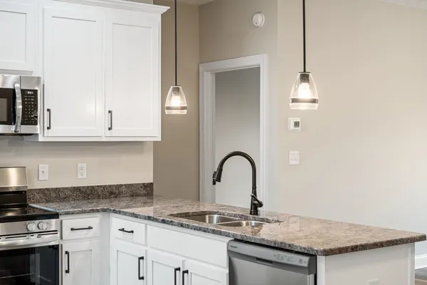 a kitchen with granite countertop a stove a sink and refrigerator