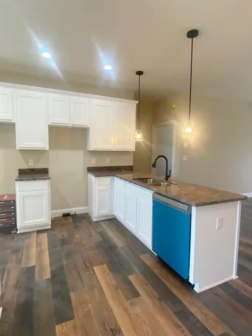 a kitchen with stainless steel appliances granite countertop a sink a stove and a wooden floors