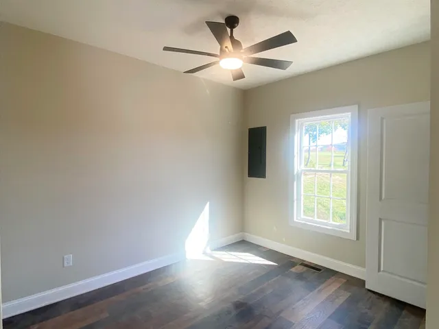 a view of an empty room with wooden floor and a window