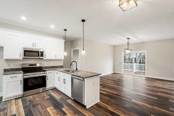 a kitchen with stainless steel appliances granite countertop a sink a stove and a wooden floors