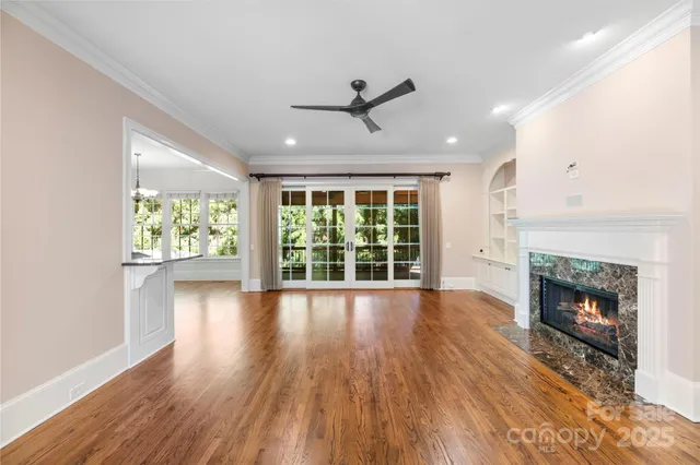 an empty room with wooden floor fireplace and windows
