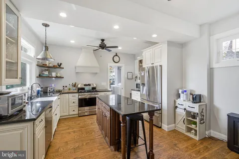 a kitchen with stainless steel appliances kitchen island granite countertop a table chairs sink and cabinets