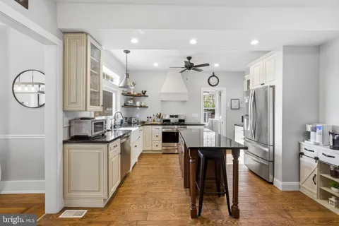 a open kitchen with stainless steel appliances granite countertop a sink a stove and a wooden floors