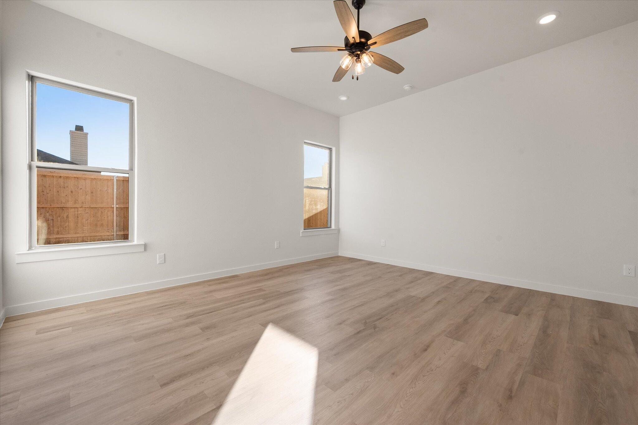 7009 56th Street Lubbock, TX 79407 - Photo 12 of 24 an empty room with wooden floor fan and windows