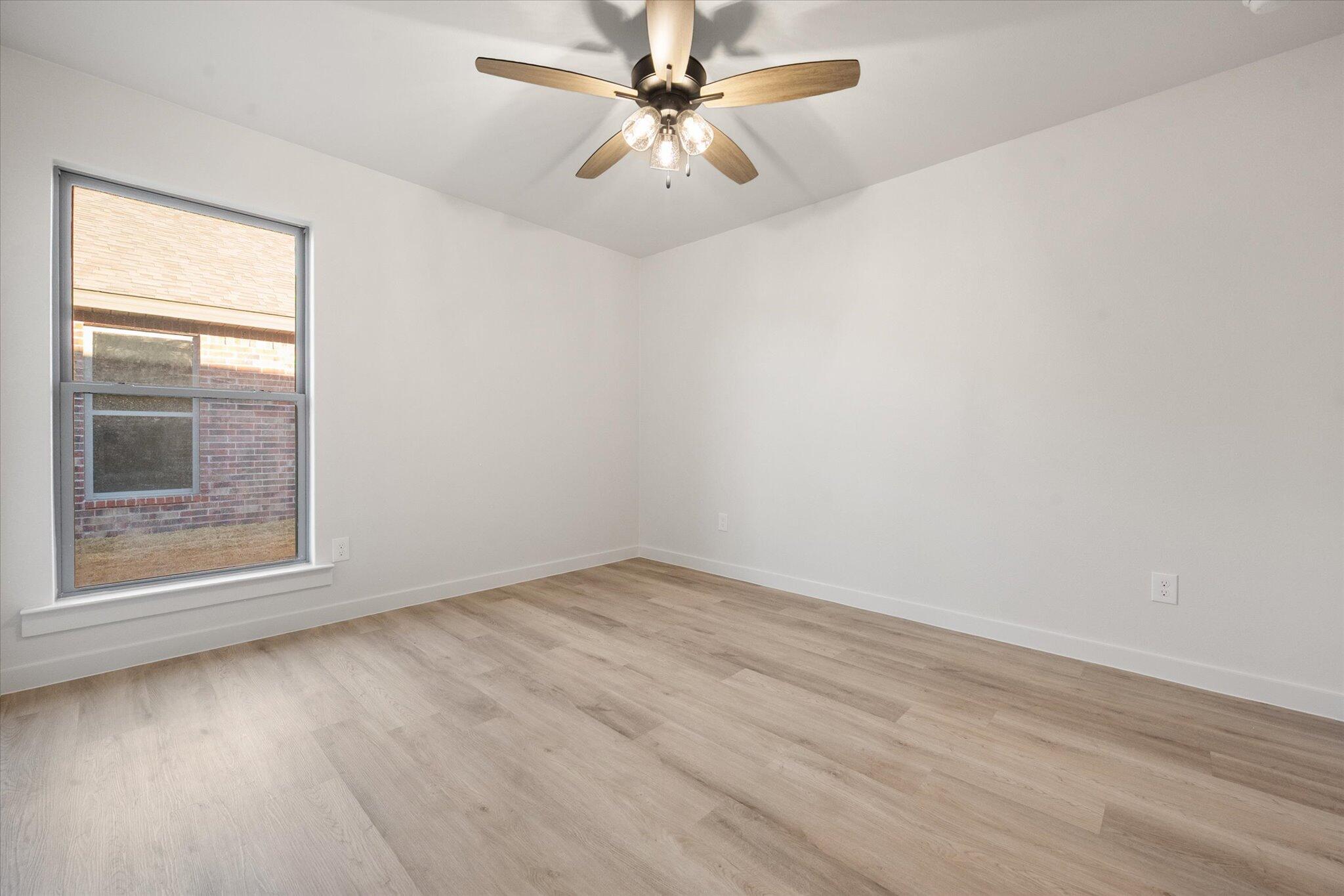 7009 56th Street Lubbock, TX 79407 - Photo 19 of 24 an empty room with a window and a ceiling fan