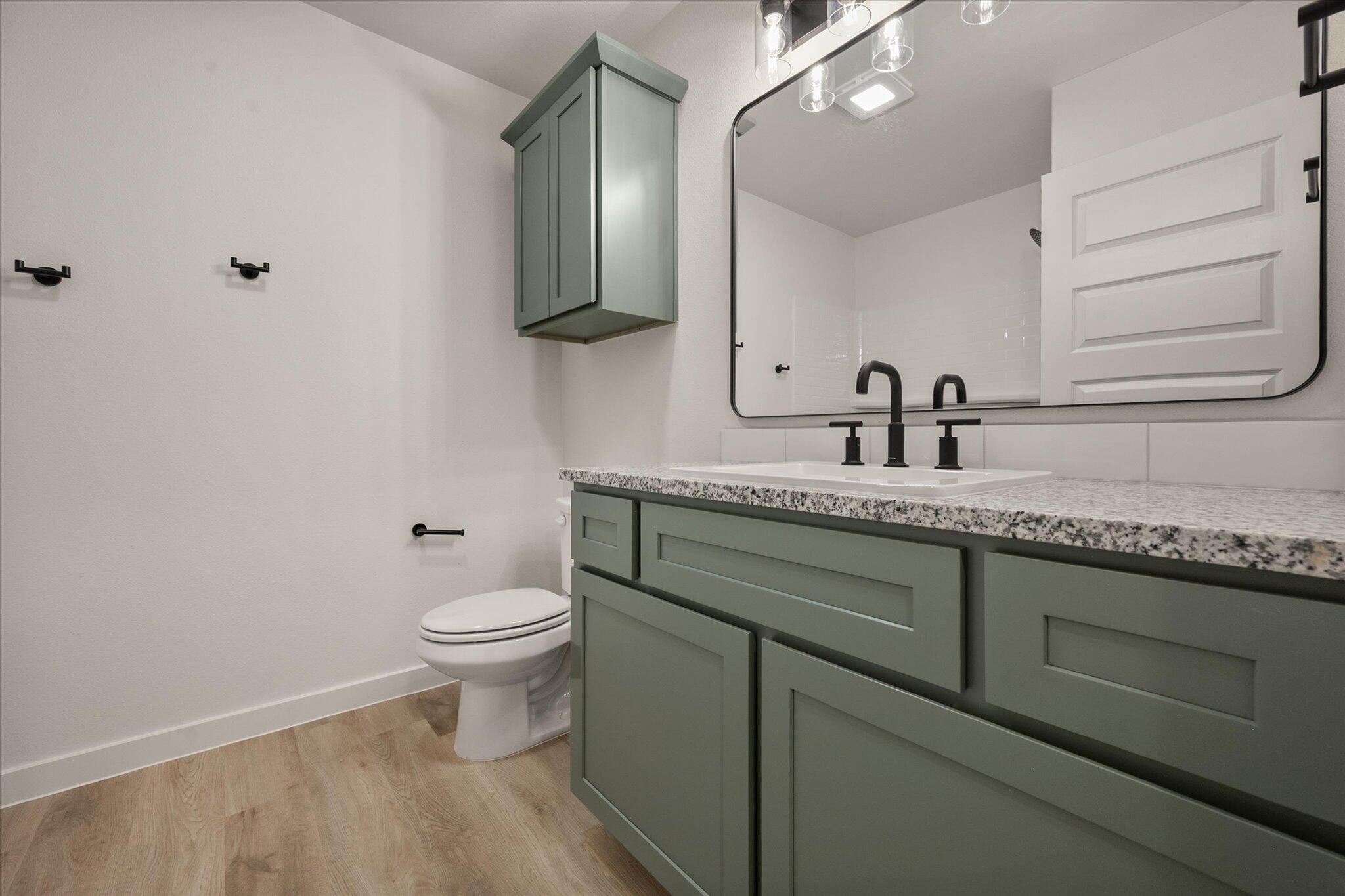 7009 56th Street Lubbock, TX 79407 - Photo 21 of 24 a bathroom with a granite countertop sink a toilet and a mirror