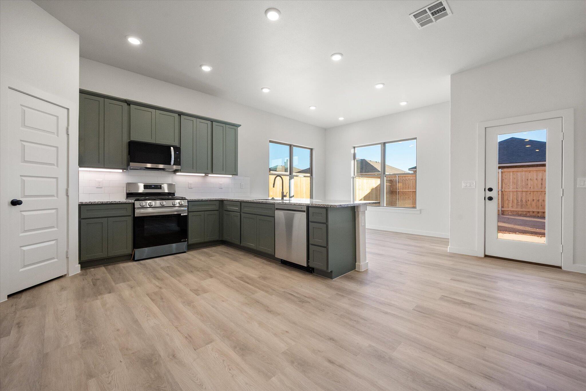 7009 56th Street Lubbock, TX 79407 - Photo 3 of 24 a large kitchen with stainless steel appliances granite countertop a stove and a sink