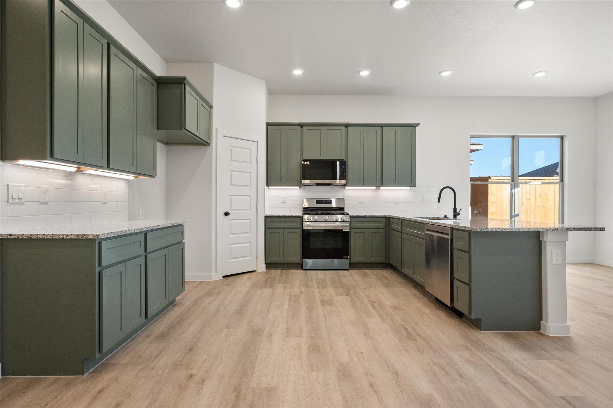 7009 56th Street Lubbock, TX 79407 - Photo 4 of 24 a kitchen with stainless steel appliances granite countertop a sink counter space cabinets and a large window