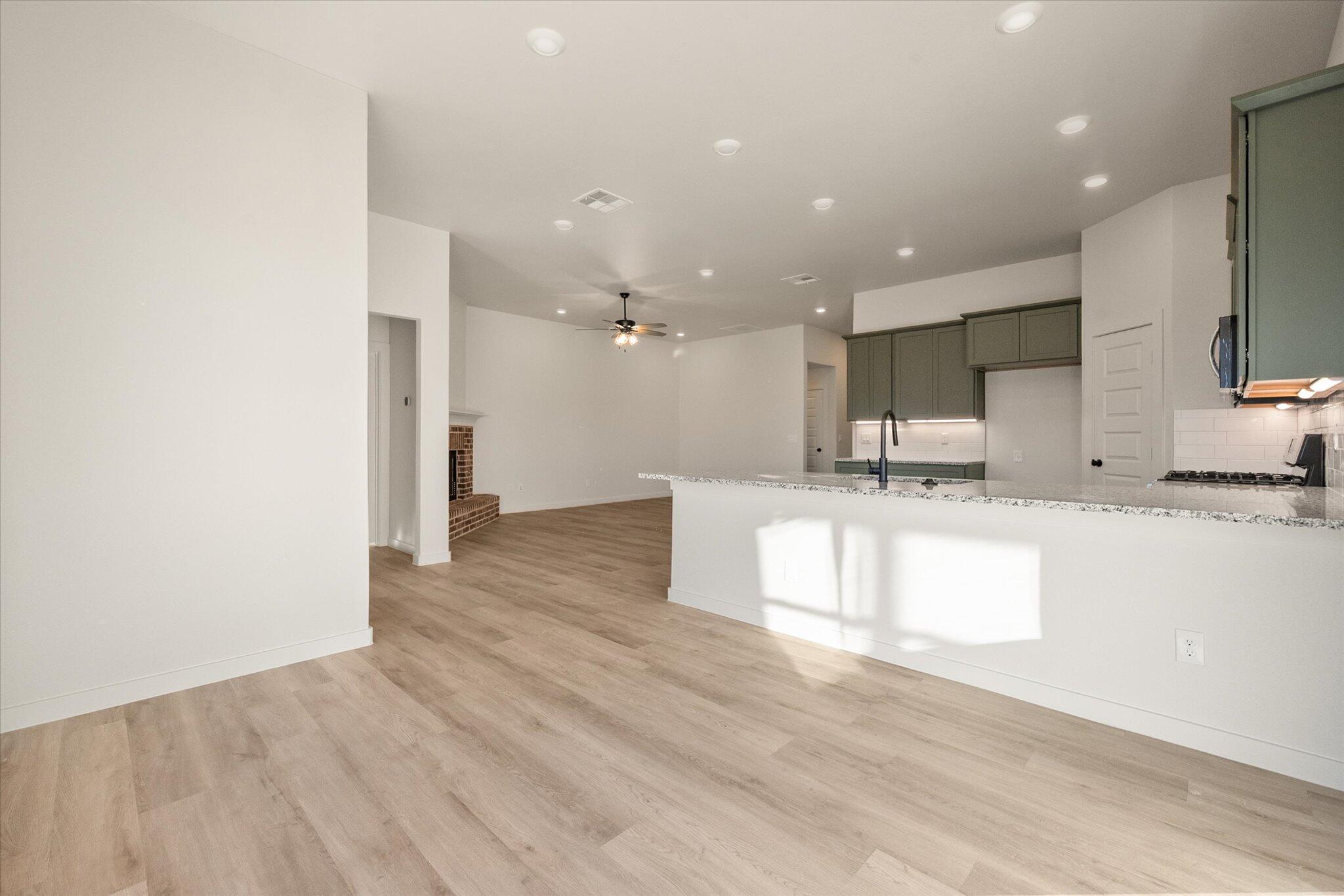 7009 56th Street Lubbock, TX 79407 - Photo 7 of 24 a view of kitchen with kitchen island a sink wooden floor and a counter top space