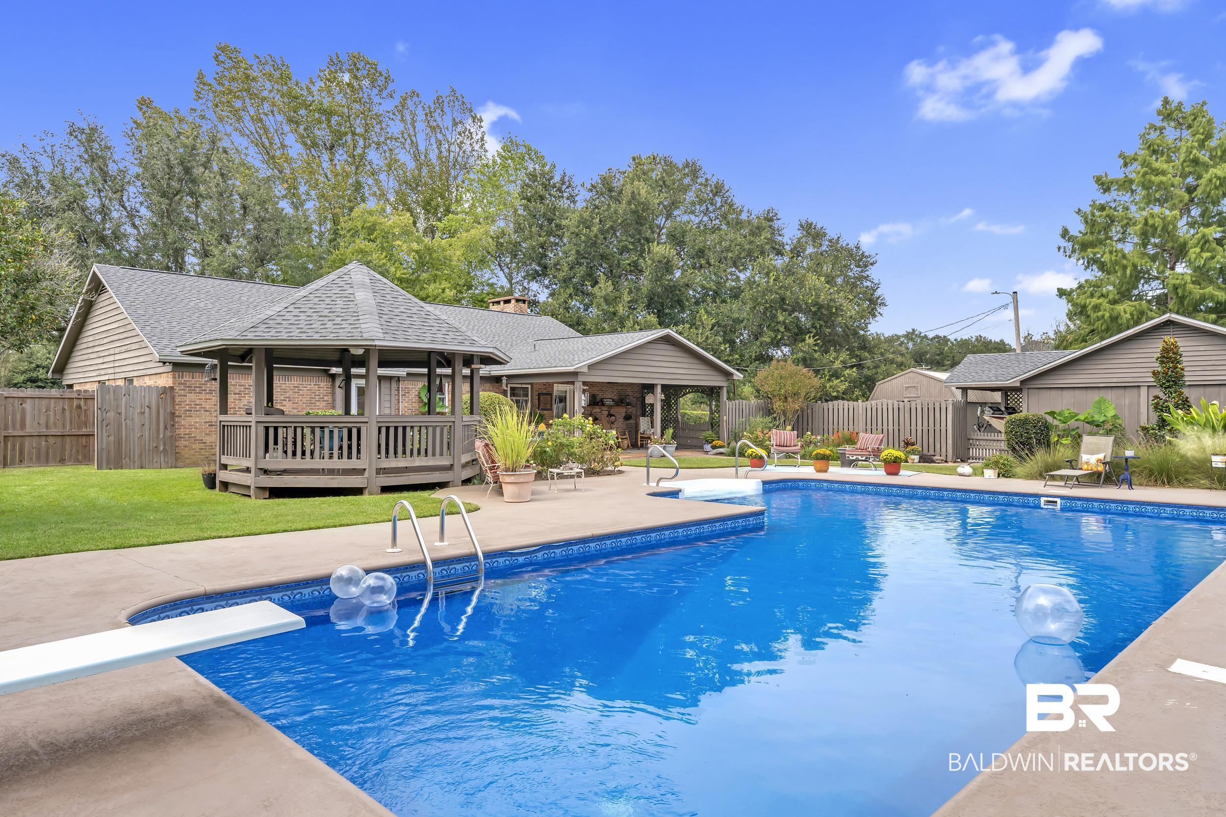19090 Gunnison Road Fairhope, AL 36532 - Photo 2 of 42 View of swimming pool featuring a fenced backyard, a diving board, a patio, and a wooden deck
