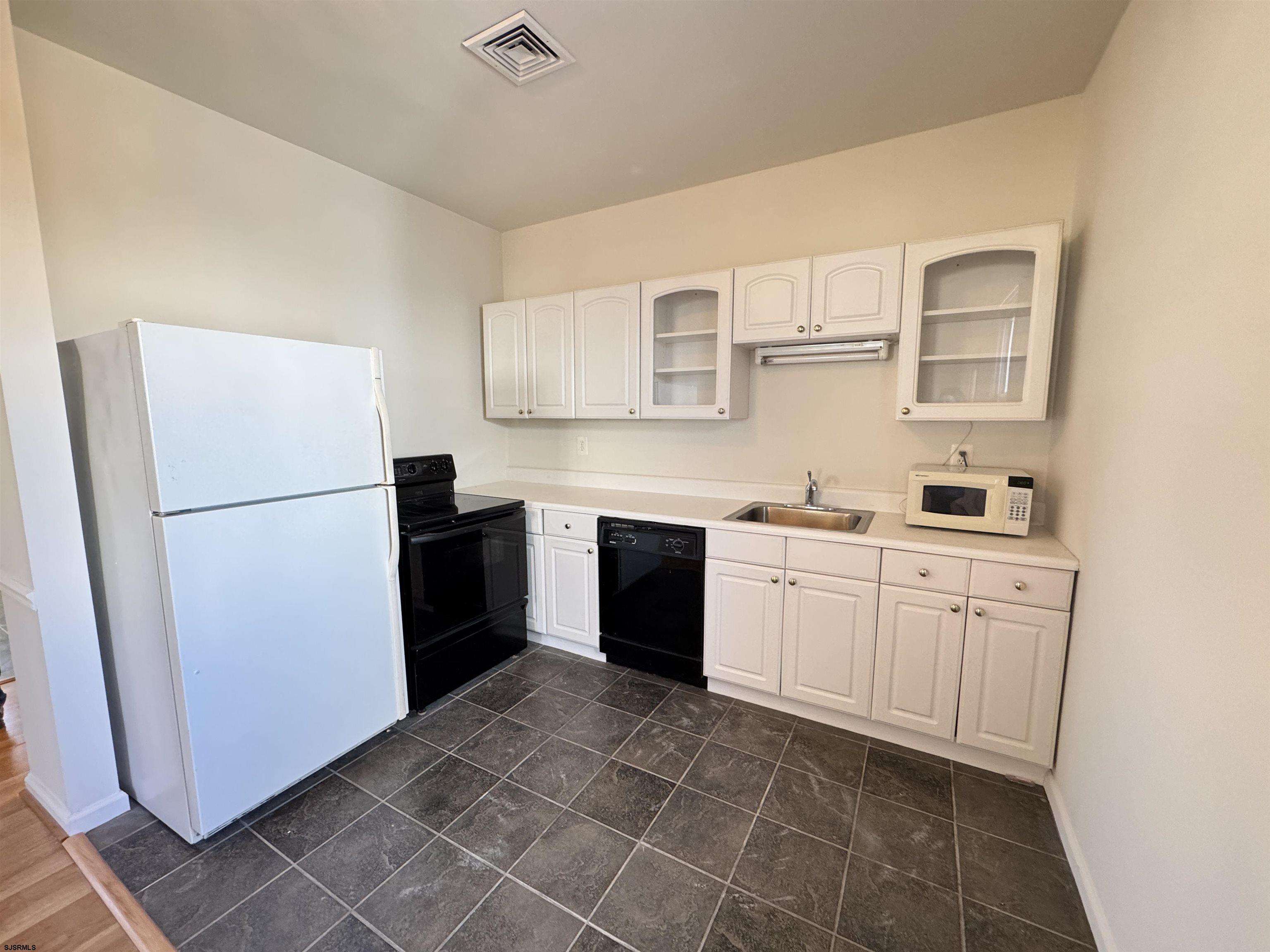 a kitchen with a refrigerator sink and cabinets