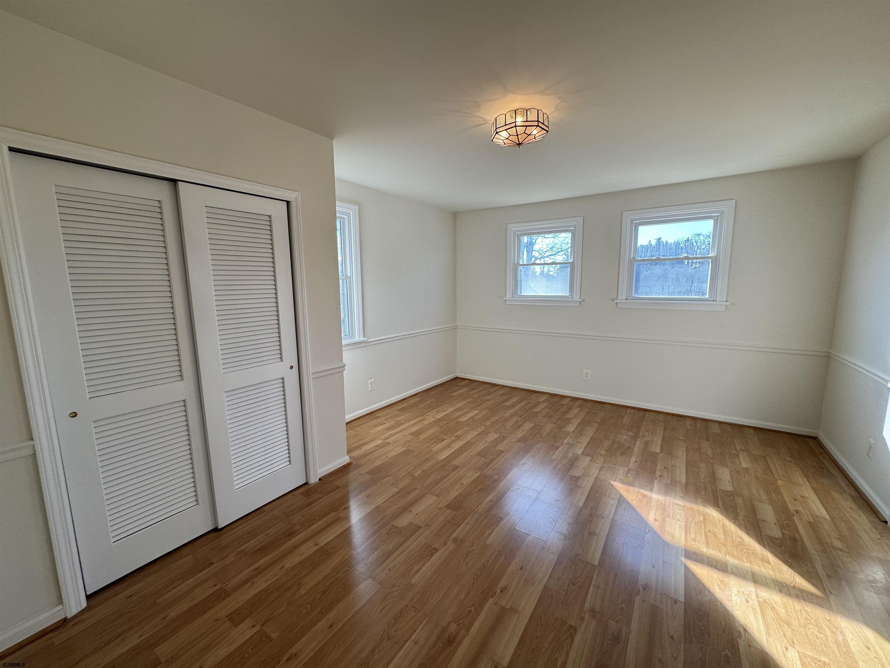 106 Harbor Road Marmora, NJ 08223 - Photo 2 of 11 an empty room with wooden floor and windows