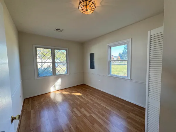 an empty room with windows and wooden floor