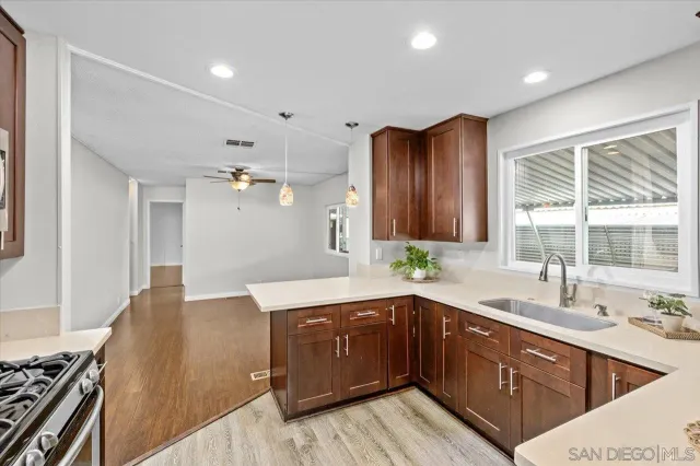 a large kitchen with a large counter top a sink stainless steel appliances and cabinets