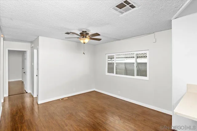 an empty room with wooden floor fan and windows