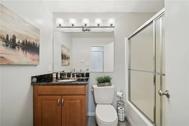 a bathroom with a granite countertop sink mirror vanity and toilet
