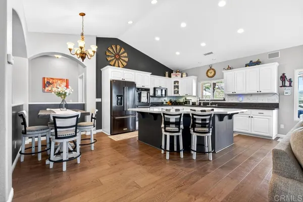 a kitchen with stainless steel appliances a dining table chairs stove and cabinets