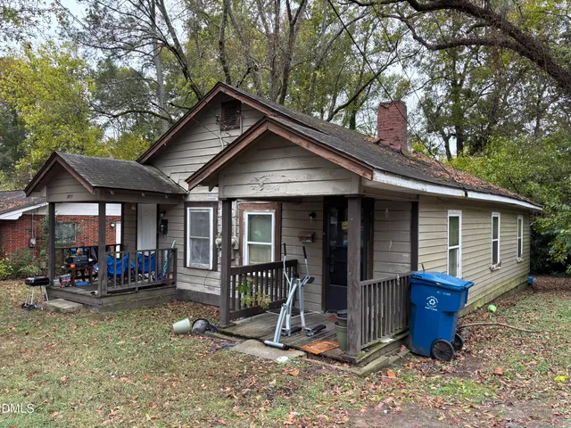 a view of a house with wooden walls and a large tree