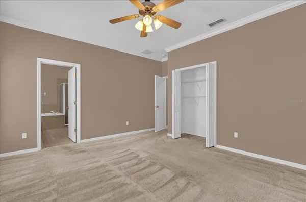 a view of an empty room and chandelier fan