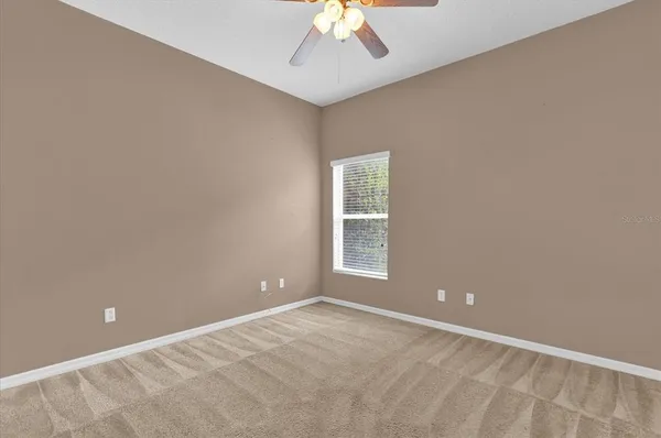 an empty room with a window and a chandelier fan