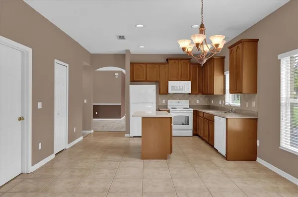 a large kitchen with a large counter top space a sink stainless steel appliances and cabinets