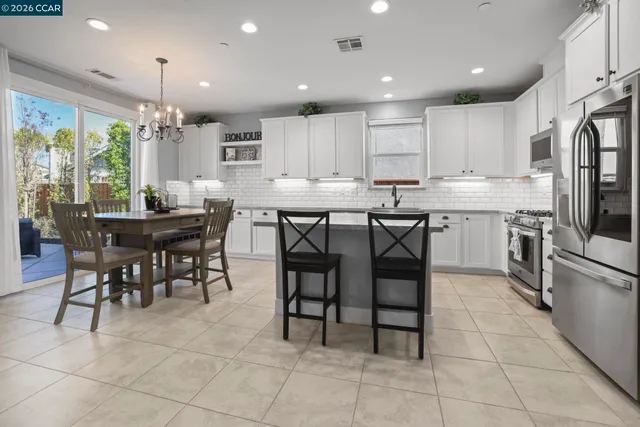a kitchen with stainless steel appliances granite countertop a table and chairs in it