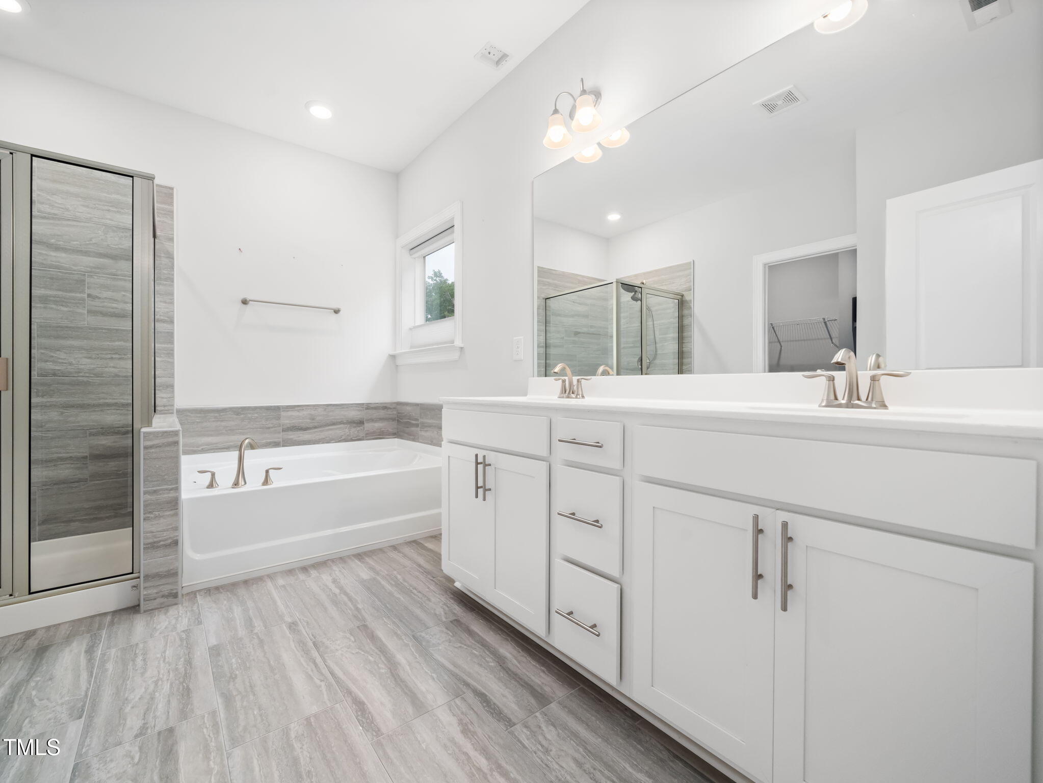 3213 Douglas Fir Road Raleigh, NC 27616 - Photo 20 of 44 a bathroom with a double vanity sink a mirror and a bathtub