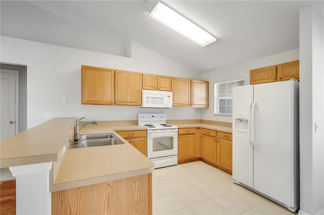 a kitchen that has a sink a stove top oven a refrigerator and a window