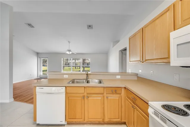 a kitchen with granite countertop a sink dishwasher a stove and white cabinets with wooden floor