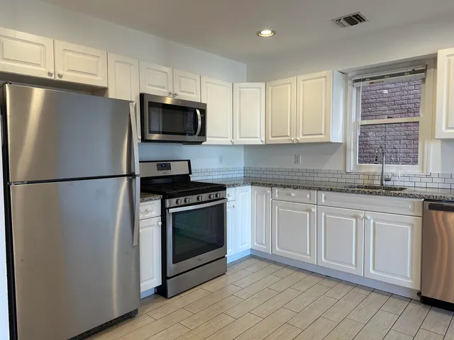 a kitchen with granite countertop a refrigerator sink and microwave