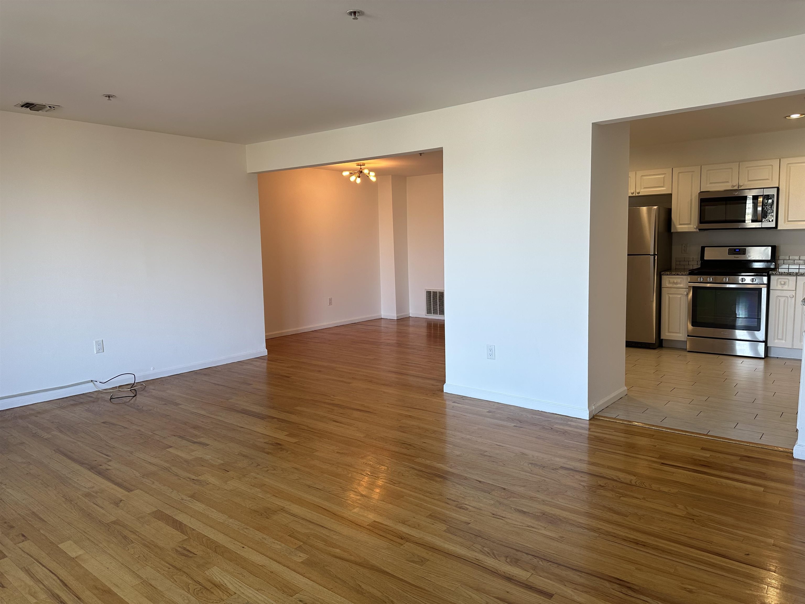 8911 Riverside Place, Unit 1 North Bergen, NJ 07047 - Photo 5 of 18 an empty room with wooden floor and windows