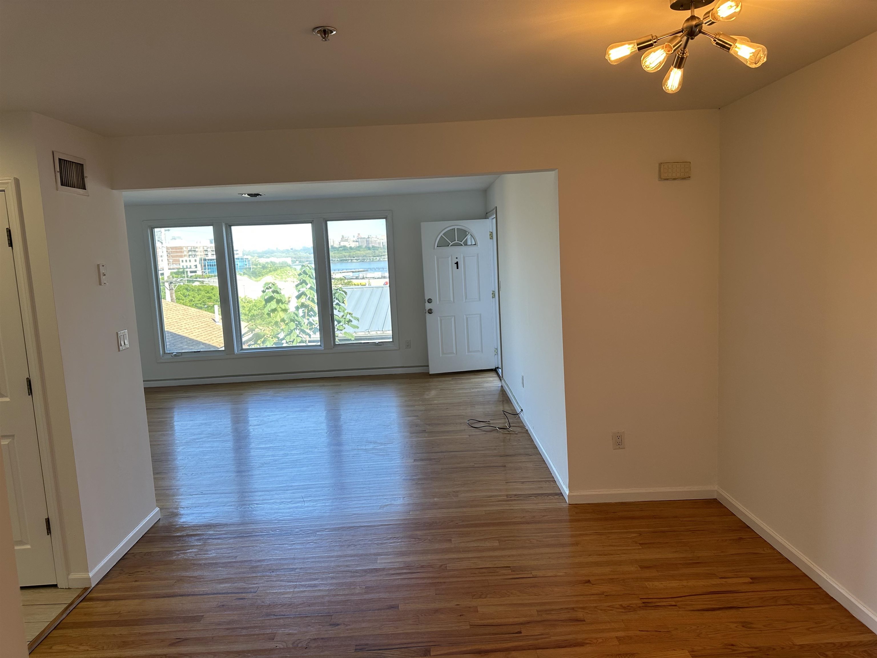 8911 Riverside Place, Unit 1 North Bergen, NJ 07047 - Photo 6 of 18 a view of an empty room with wooden floor and a window