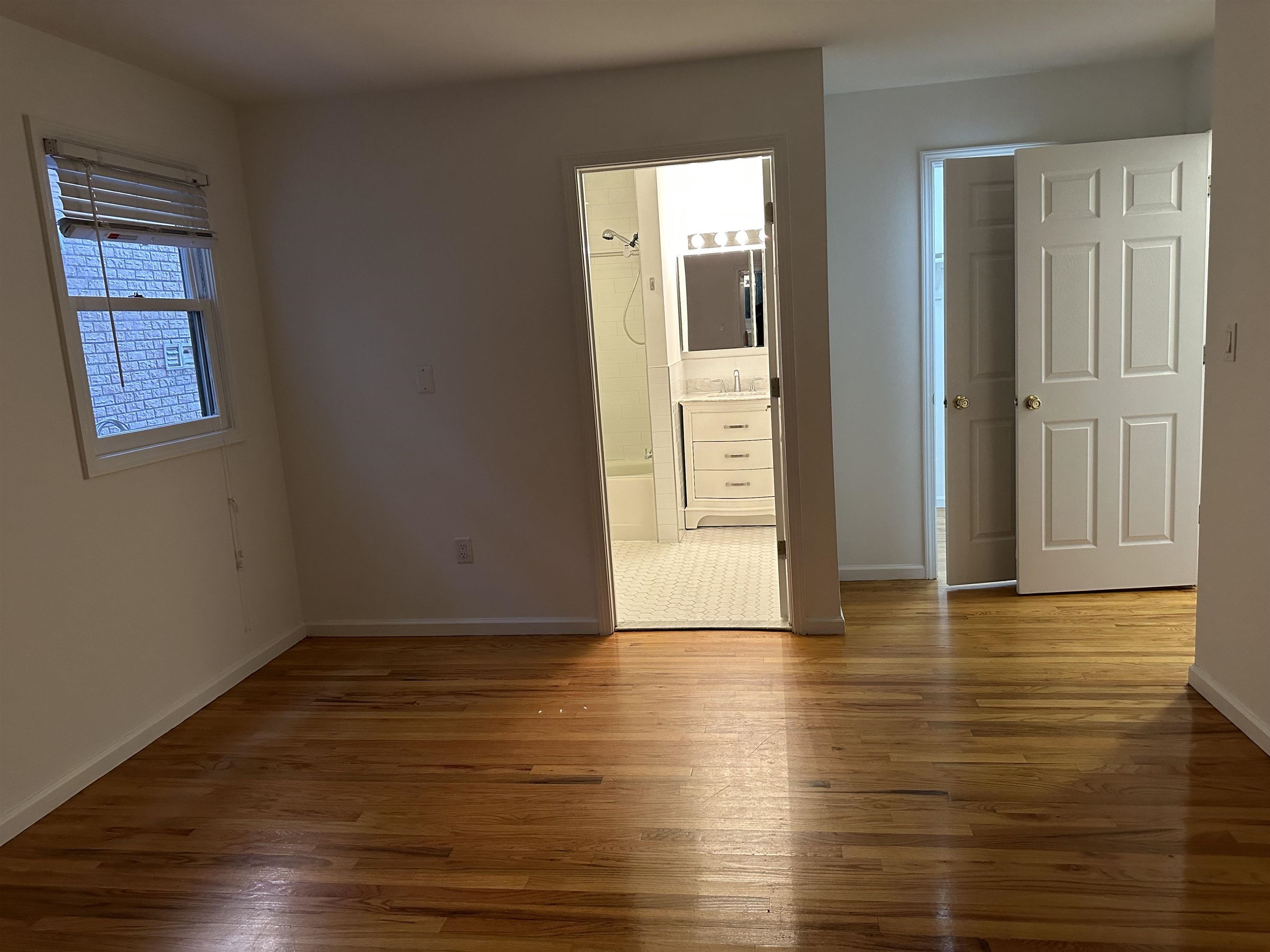 8911 Riverside Place, Unit 1 North Bergen, NJ 07047 - Photo 7 of 18 a view of an empty room with wooden floor and a window