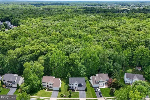 an aerial view of residential house with outdoor space and trees all around